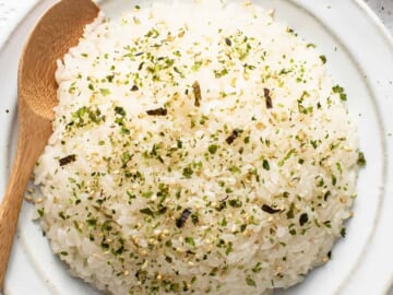 Japanese rice on a white plate with a wooden spoon.