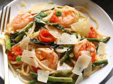 Shrimp scampi with asparagus served over a plate of pasta.