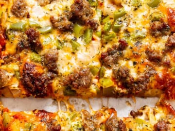 Close-up of a cheesy pizza with sausage and green peppers.