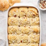 Freshly baked almond-topped sweet rolls in a white baking dish.