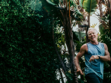 Mark smiles mid-stride in front of a grove of trees.