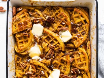 Pumpkin waffles in a baking dish with butter and pecans.