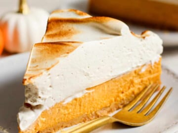 A slice of pumpkin pie on a plate with a fork.