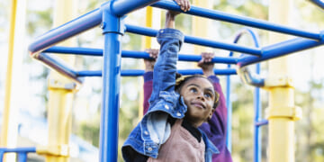 girl playing on playground monkey bars