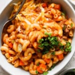 A bowl of macaroni and cheese with meat and vegetables.