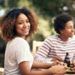 Portrait of a young woman having a meal with friends outdoors.