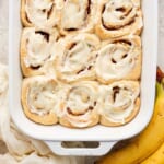 Cinnamon rolls in a baking dish with bananas.