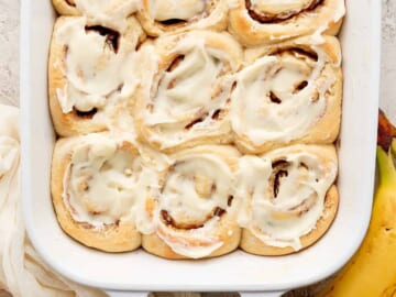Cinnamon rolls in a baking dish with bananas.