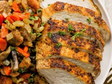 A plate of roasted chicken and vegetables on a white plate.