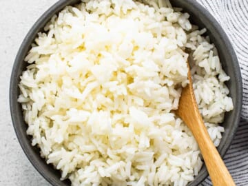 White rice in a bowl with a wooden spoon.