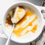 A bowl of ice cream with caramel sauce and a spoon.