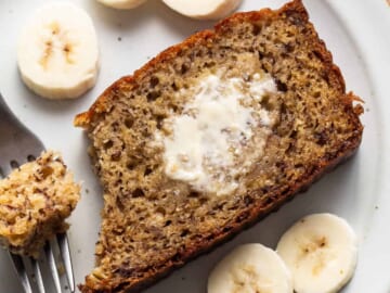 A slice of banana bread on a plate with a fork.