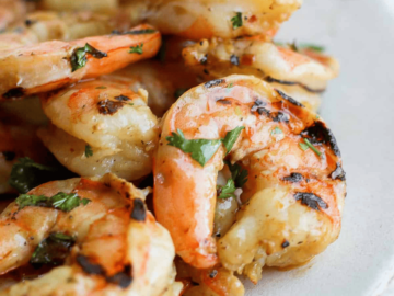 Grilled shrimp on a plate with lemon wedges, marinated.