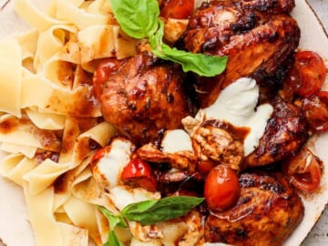 Grilled chicken with pasta and tomatoes on a plate.