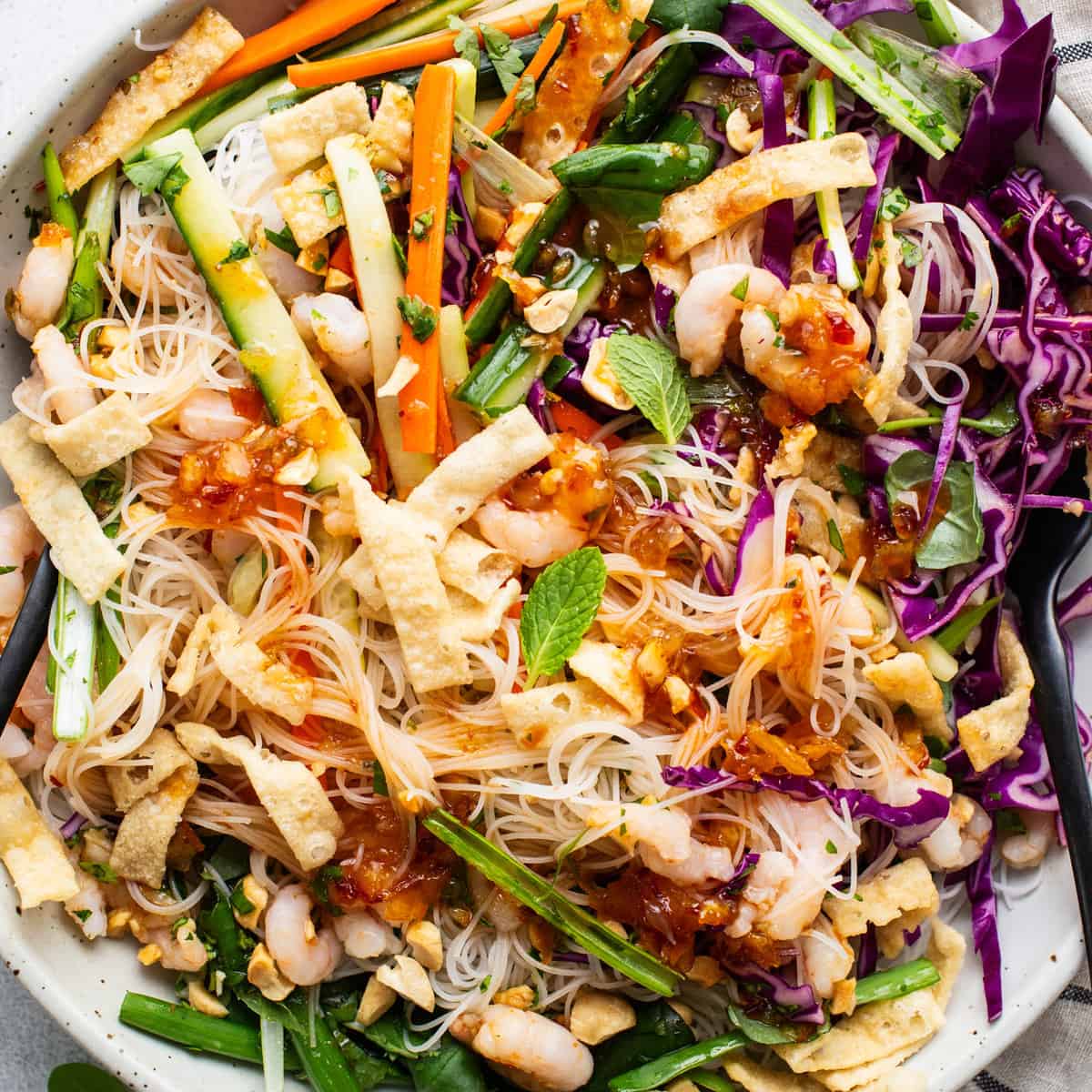 A bowl of asian noodle salad with shrimp and vegetables.