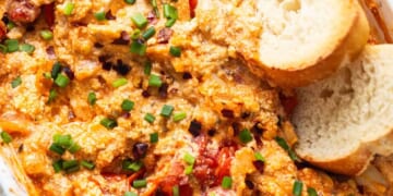 A casserole dish with chicken, tomatoes and bread.