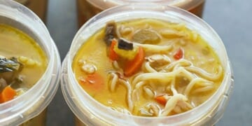 Four plastic containers filled with soup are frozen.