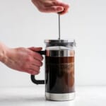 A person making coffee with a French press.