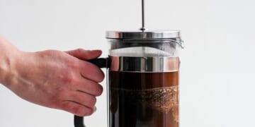 A person making coffee with a French press.