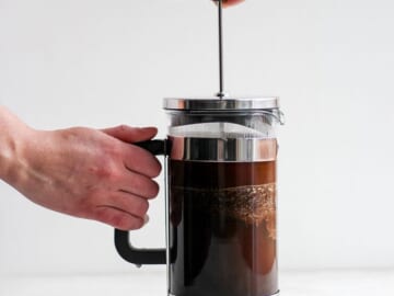 A person making coffee with a French press.