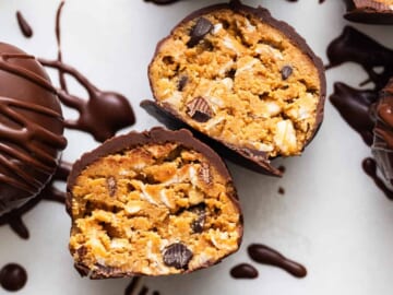 Chocolate covered peanut butter truffles on a white surface.