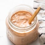 A jar of ketchup with a wooden spoon.