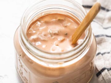 A jar of ketchup with a wooden spoon.