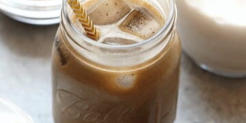 A jar of cold brew protein drink with a straw next to it.