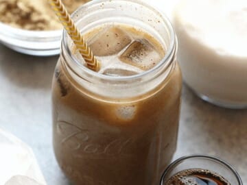 A jar of cold brew protein drink with a straw next to it.