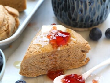 Honey whole wheat scones with blueberries and jam on a tray.