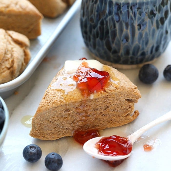 Honey whole wheat scones with blueberries and jam on a tray.