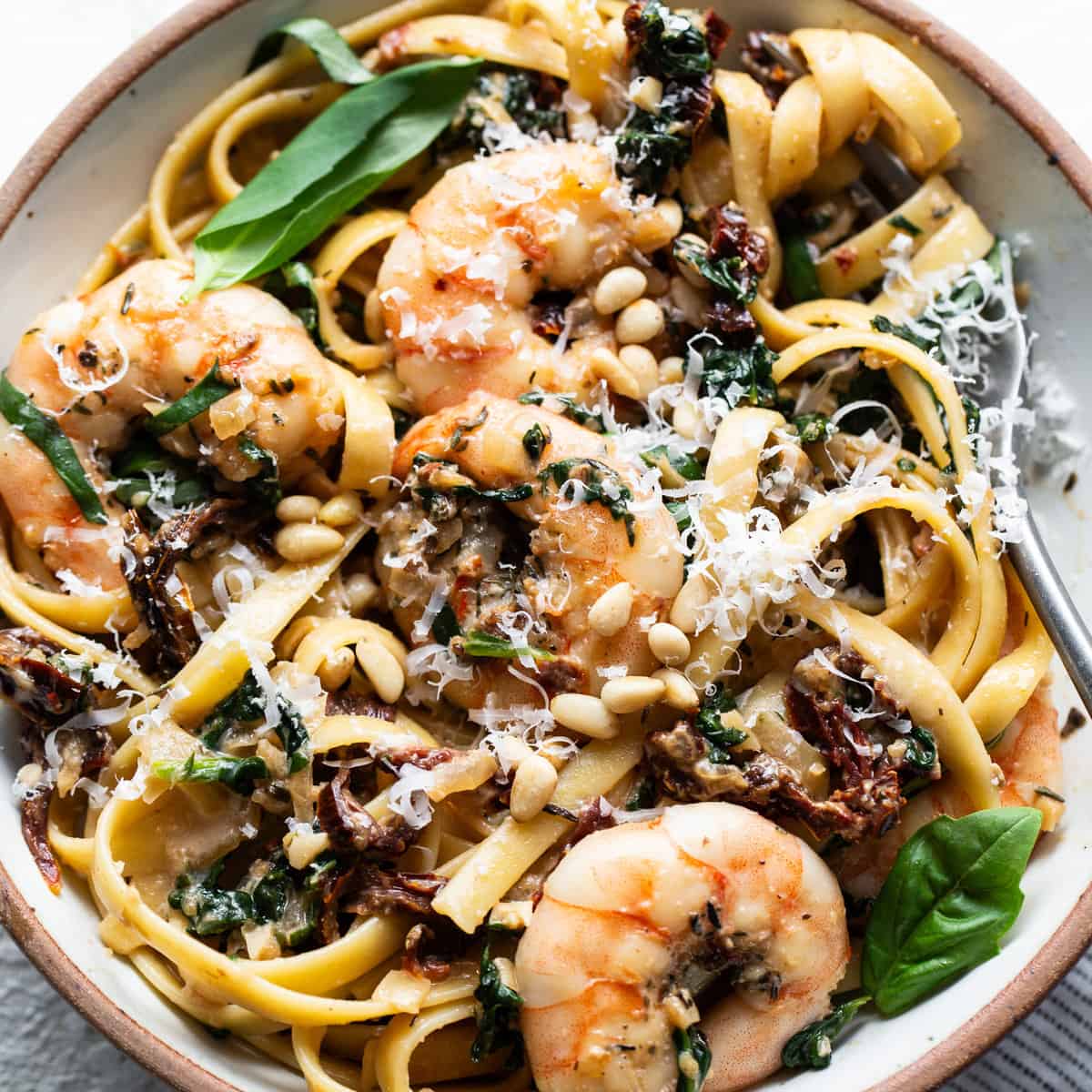 A bowl of pasta with shrimp and spinach.