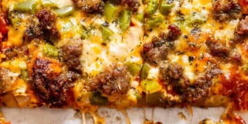 Close-up of a cheesy pizza with sausage and green peppers.